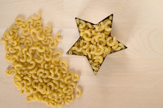 Macaroni forming a star over a wooden cut board