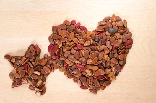 Heart shape red roasted watermelon seed on wooden cut board