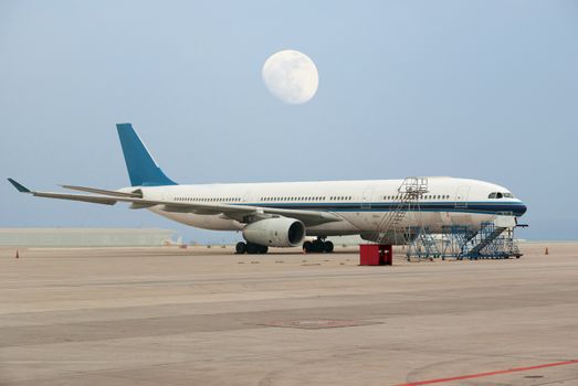 Commercial airline on platform airport with the full moon in the background