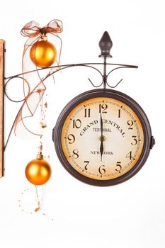 Time for coming together and festive dinner. Traditional classic clock decorated with golden xmas decoration and ribbon.