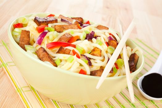 Noodles with tofu and vegetable, chopsticks and soy sauce. Asian food concept.