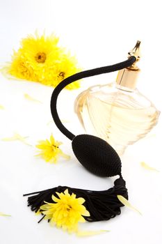 Vintage perfume bottle atomizer with yellow flowers isolated on white background. Feminine beauty concept.