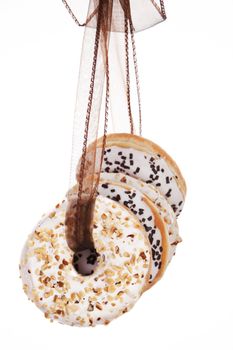 Luxurious donuts still life. Various donuts hanging on brown ribbon. Culinary sweets.