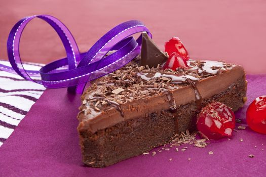 Delicious chocolate cake on purple background. Culinary sweet desert still life.