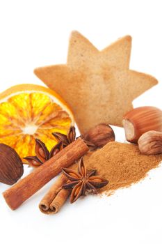Natural christmas still life with cinnamon, various nuts, gingerbread cookie and orange on white background.