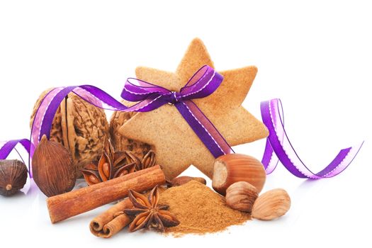 Gingerbread star cookie with hazelnut, cinnamon and purple ribbon. Natural brown christmas still life. Aromatic culinary spices and various nuts.