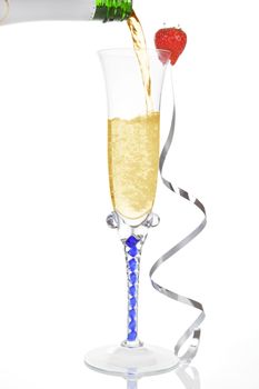 Pouring golden champagne into a glass with silver ribbon isolated on white. Luxury new year concept.
