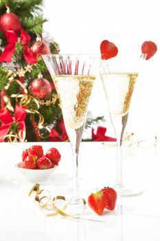 Champagne and strawberries, christmas tree in background. Festive xmas.