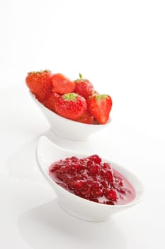 Delicious strawberry marmalade in white bowl and fresh strawberries in background on white. Fresh summer fruit concept.