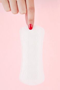 Female hand with red fingernails holding clean pantyliner. Feminine hygiene concept.