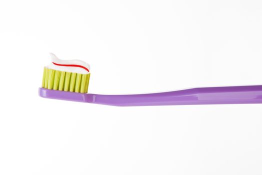 Purple toothbrush with striped red and white toothpaste isolated on white background. Dental hygiene concept.