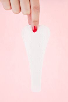 Female hand with red fingernails holding clean g - string pantyliner. Feminine hygiene concept.