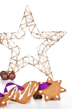 Homemade delicious gingerbread stars and heart with purple ribbon with big christmas star decoration. Temporary christmas background.