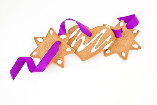 Homemade delicious gingerbread stars and heart with purple ribbon isolated over white. Traditional christmas background.