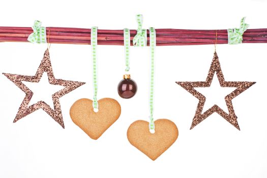 Traditional christmas background. Gingerbread hearts, stars and christmas ball hanging from branches.