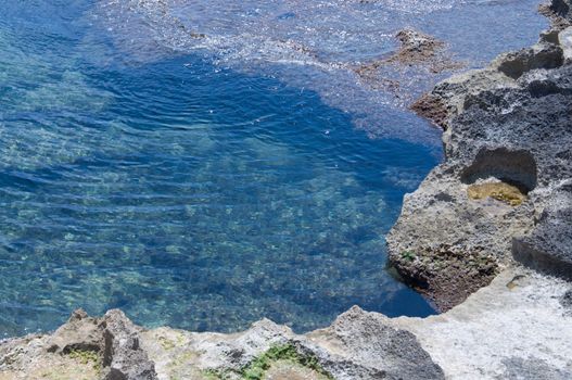 Pool of green ocean water by red and white limestone rocks. Majorca, Balearic islands, Spain.