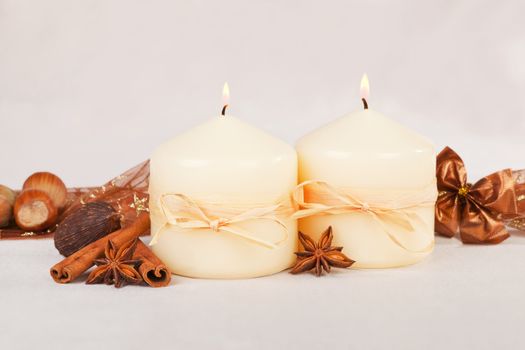 Beautiful traditional christmas still life with burning candles, almond, nuts. ribbon and brown decoration.