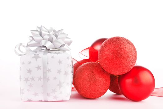 Luxurious present and christmas balls with ribbon on light pink background. Festive holiday background, giving concept.