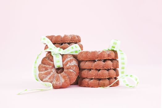 Delicious chocolate cookies with green ribbon isolated on pink background. Christmas sweets cocnept.