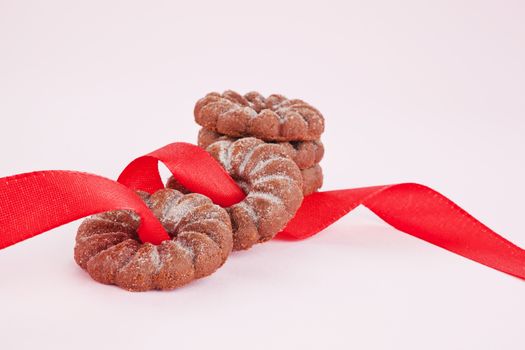 Chocolate cookies with red ribbon on pink background. Sweets.