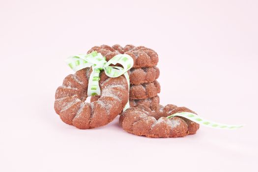 Delicious chocolate cookies with green ribbon isolated against pink background.