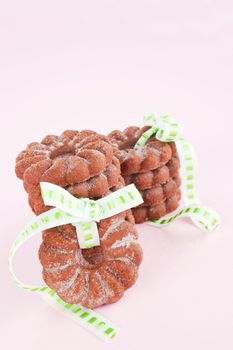 Delicious chocolate cookies with green ribbon against pink background. Christmas sweets.