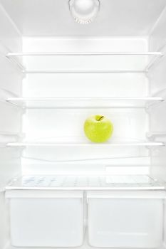 One apple in open empty white refrigerator. Weight loss diet concept.