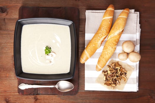 Delicious mushroom cream soup in bowl with pastry, fresh and dried mushrooms. Culinary eating. Top view.