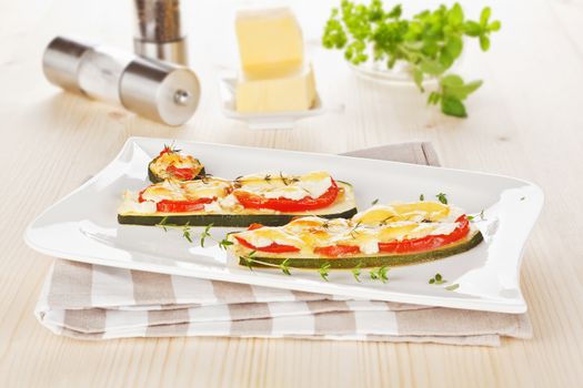 Luxurious baked zucchini slices with tomato and cheese. Culinary vegetarian eating.