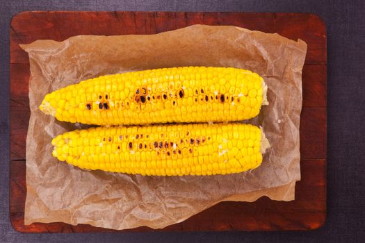 Boiled and roasted golden corn on a piece of baking paper. Culinary healthy vegetable.