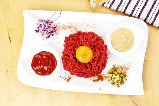 Traditional steak tartare with yolk on white plate. Culinary eating. 