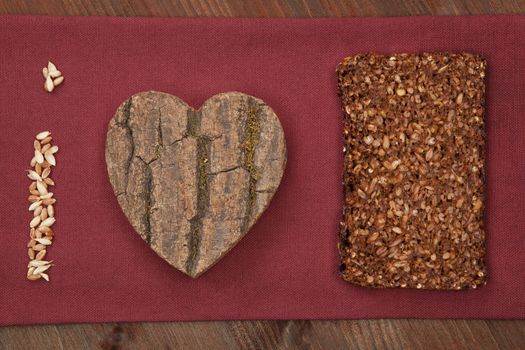 I love black bread made of dark bread slice, wooden heart and grain. Healthy lifestyle background.