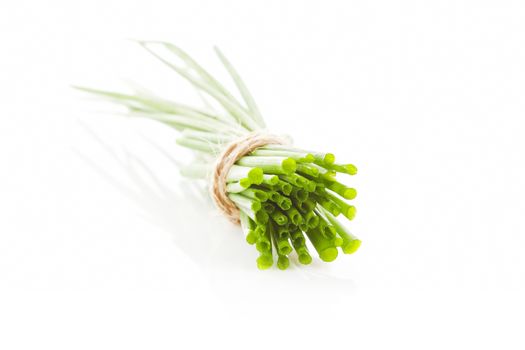 Fresh organic chive bundle bound with brown twine isolated on white background. Aromatic culinary herbs.