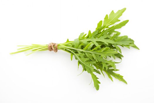 Arugula bunch bound with brown twine isolated on white background. Culinary aromatic fresh herbs.
