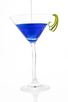 Pouring cream into blue cocktail in cocktail glass isolated on white background.