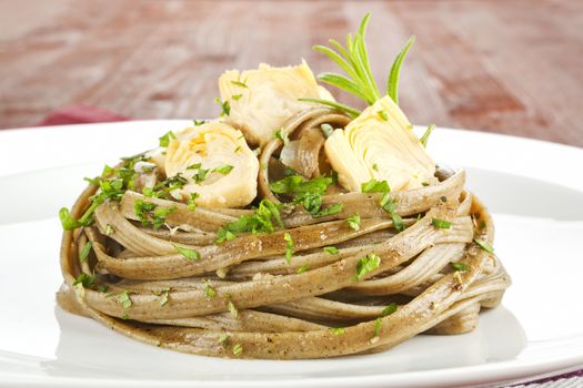Pasta with artichoke hearts on white plate close up. Luxury culinary eating.