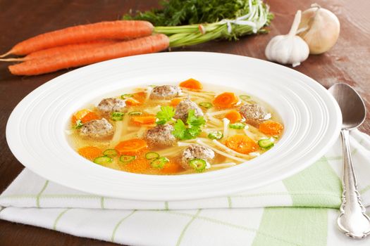 Vegetable soup in white plate with fresh vegetable in background. Rustic style healthy eating concept.