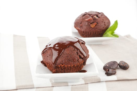 Chocolate muffins in luxurious bowls decorated with fresh mint leaf on kitchen cloth. Luxurious muffin background.