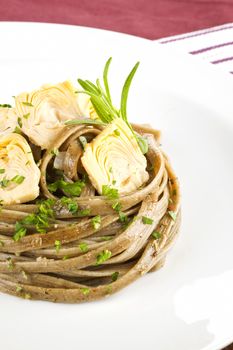 Luxurious homemade pasta with artichoke hearts on white plate. Exquisite dining. 