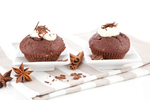 Two muffins with cream and chocolate. Luxurious sweets concept.