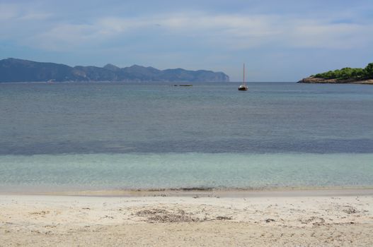 Turquoise bay and moored sailing boat, Mallorca in October.