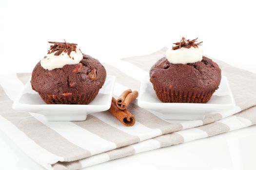 Two delicious muffins decorated with cream and chocolate. Luxurious sweet food.