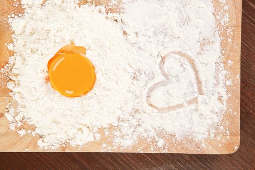 Flour and yolk on wooden board on brown table. Baking background.