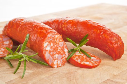 Luxurious hungarian traditional sausage on wooden board with fresh herbs.