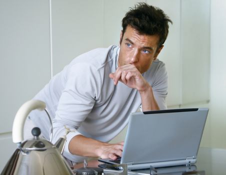 man is working on laptop computer in kitchen