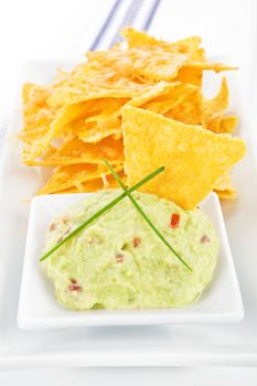 Delicious nachos baked with cheese with guacamole dip isolated on white background.