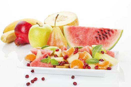 Colorful fruit salad and fruits on white plate isolated. Fresh summer background. When it comes to eating right and exercising, there is no "I'll start tomorrow."  Tomorrow is disease.