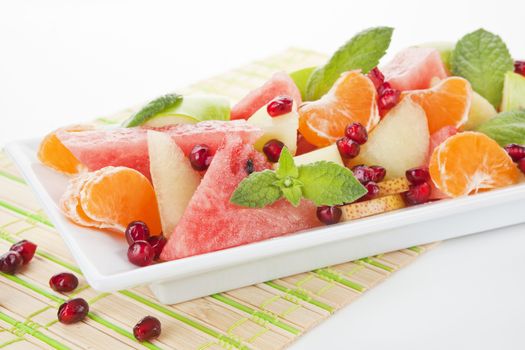 Fresh tropical fruit salad in white plate. Summer background.