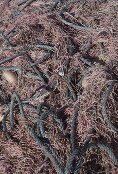 Black and brown fishing nets and ropes tangled together full frame.