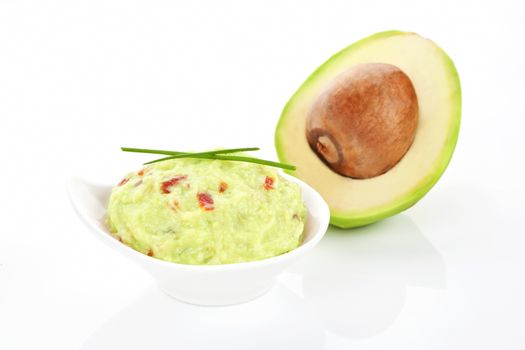 Guacamole dip in bowl and fresh delicious avocado isolated on white. 